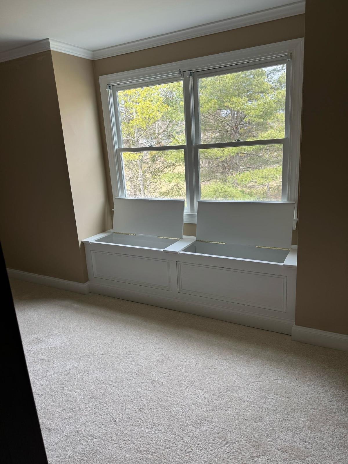 Built-in window seat with panelled fronts under a pair of bay windows