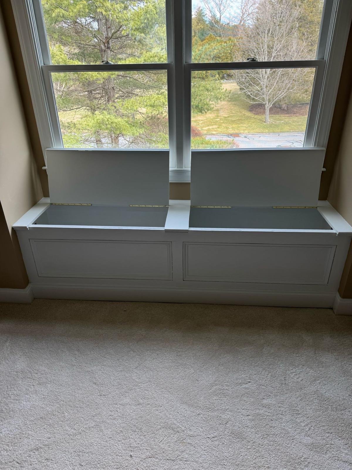 Finished built-in window seat with two panelled storage compartments under a window