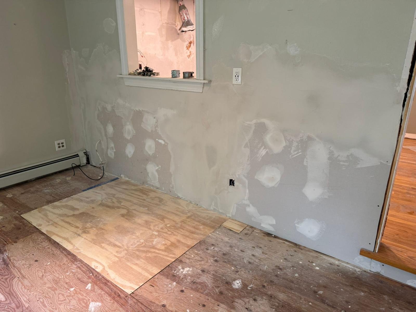 Room with patched walls and bare subfloor before a Seven Pines interior renovation