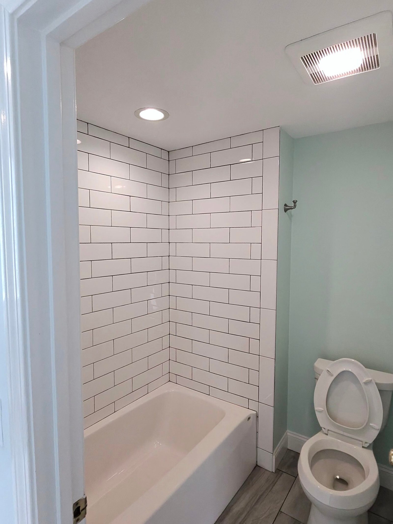 Bathroom with a white subway tile tub surround and tiled floor in Needham, MA