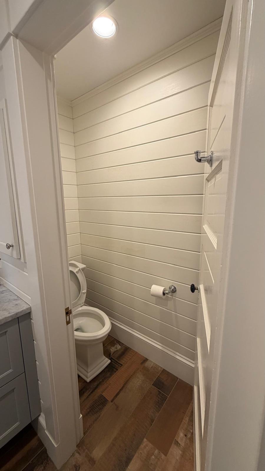 Shiplap powder room with wood-look tile flooring in a Newton, MA renovation