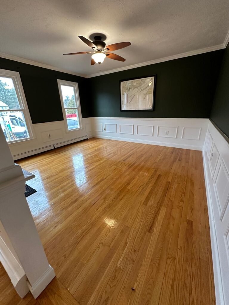 Room painted deep green with white crown moulding, wainscoting and window casing