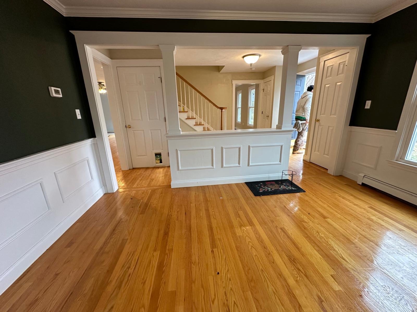 Entry hall with panelled wainscoting, painted doors and an open stair beyond