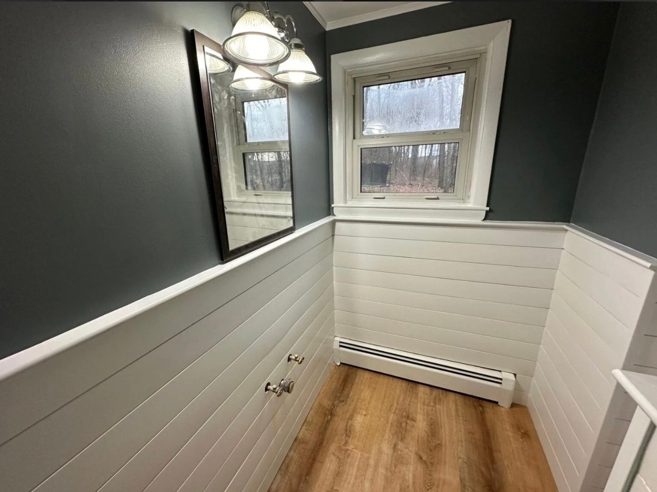 Hallway with white shiplap wainscoting, dark painted walls above and a plank floor