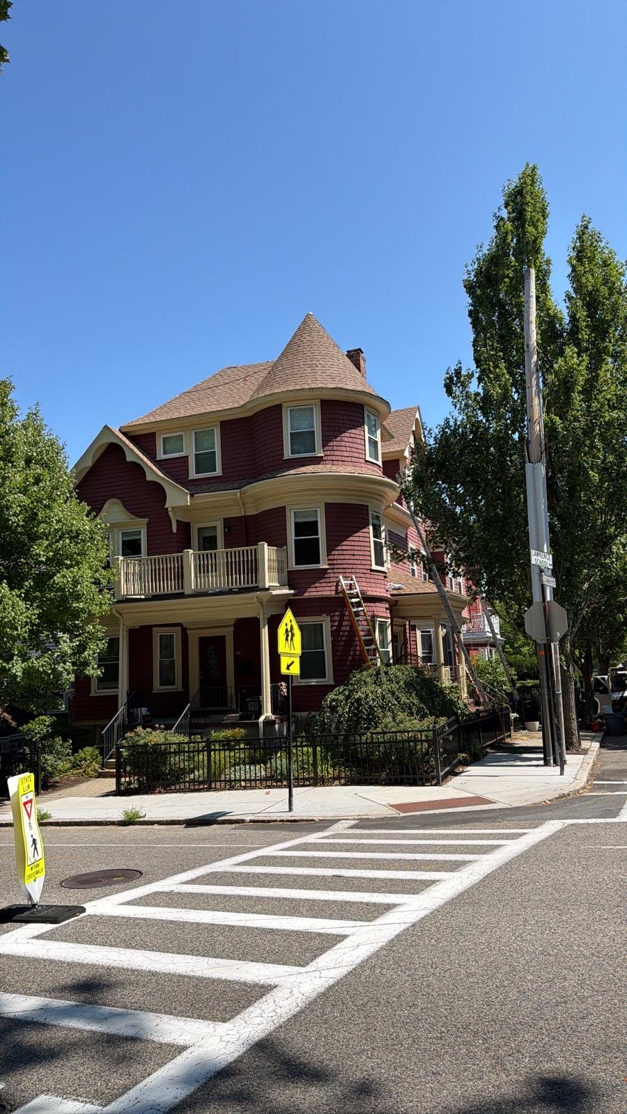 Victorian home in Shrewsbury, MA with a corner turret and a newly shingled roof, seen from the street