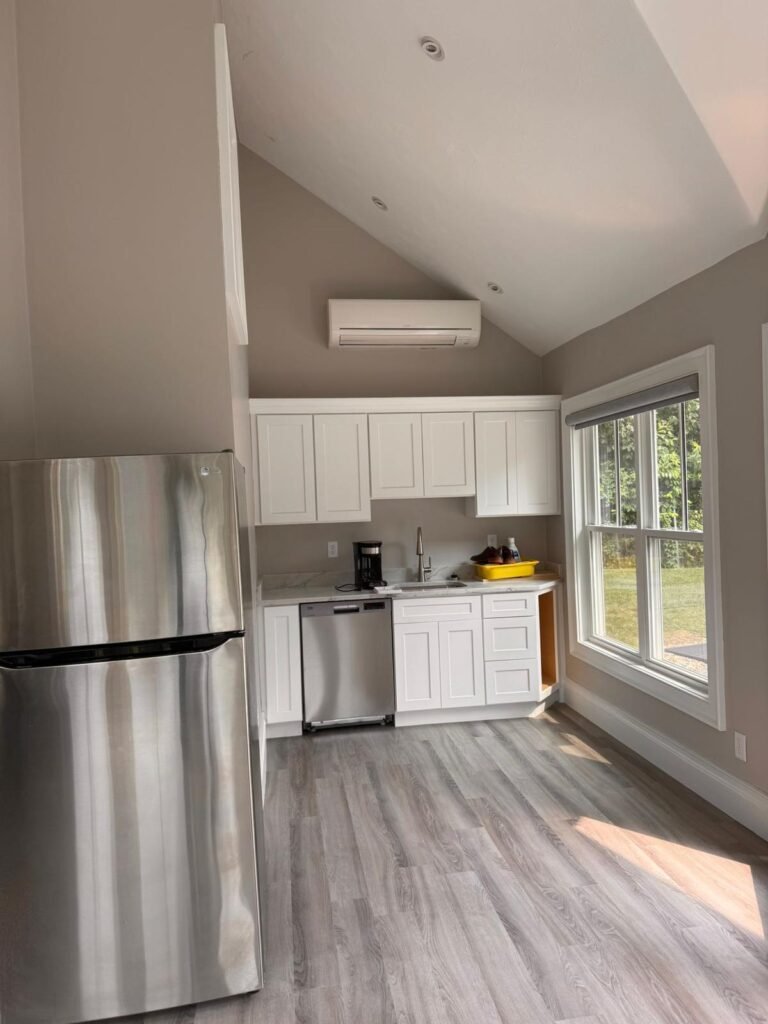 Small kitchen with white shaker cabinets, a vaulted ceiling, stainless appliances and plank flooring