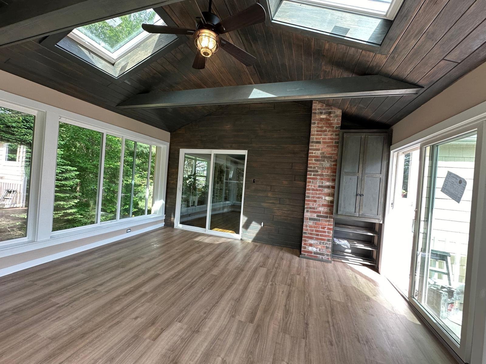 Finished sunroom addition with a stained vaulted ceiling, skylights and an exposed brick chimney