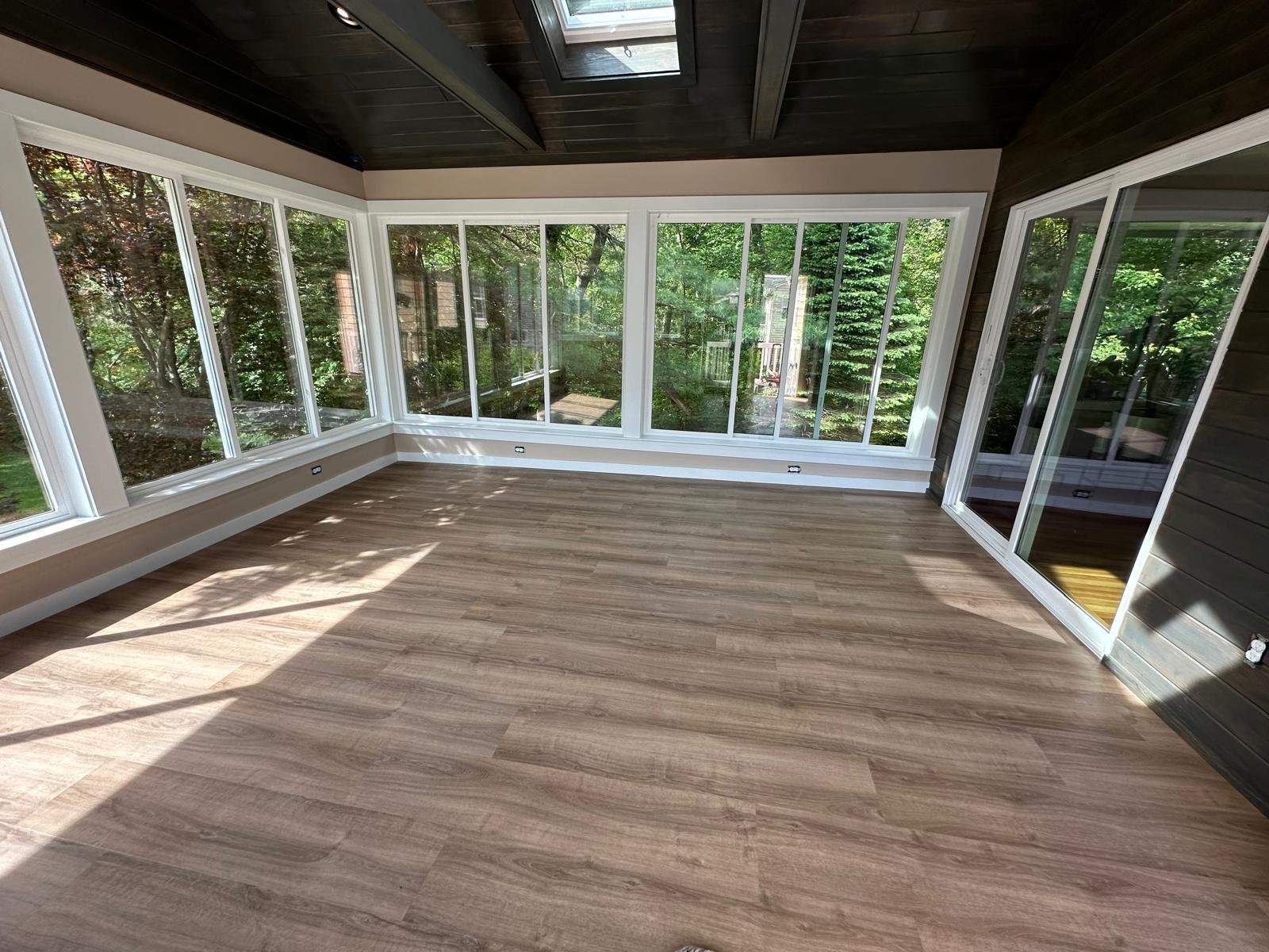 Sunroom addition with a full wall of windows, sliding doors and wide plank flooring