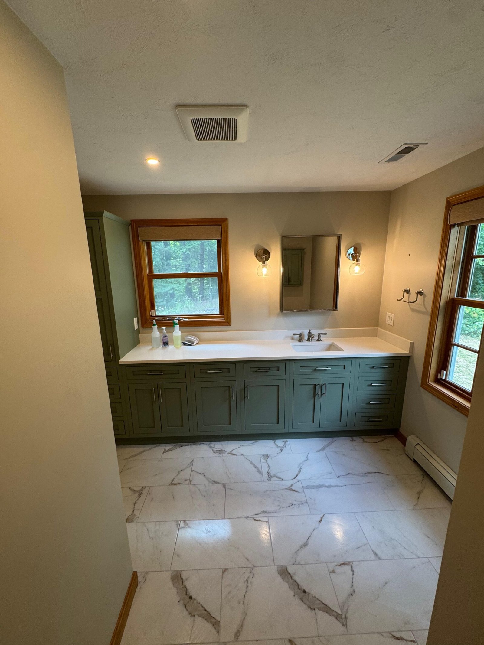 Master bathroom in Weston, MA with a green double vanity and marble-look tile floor
